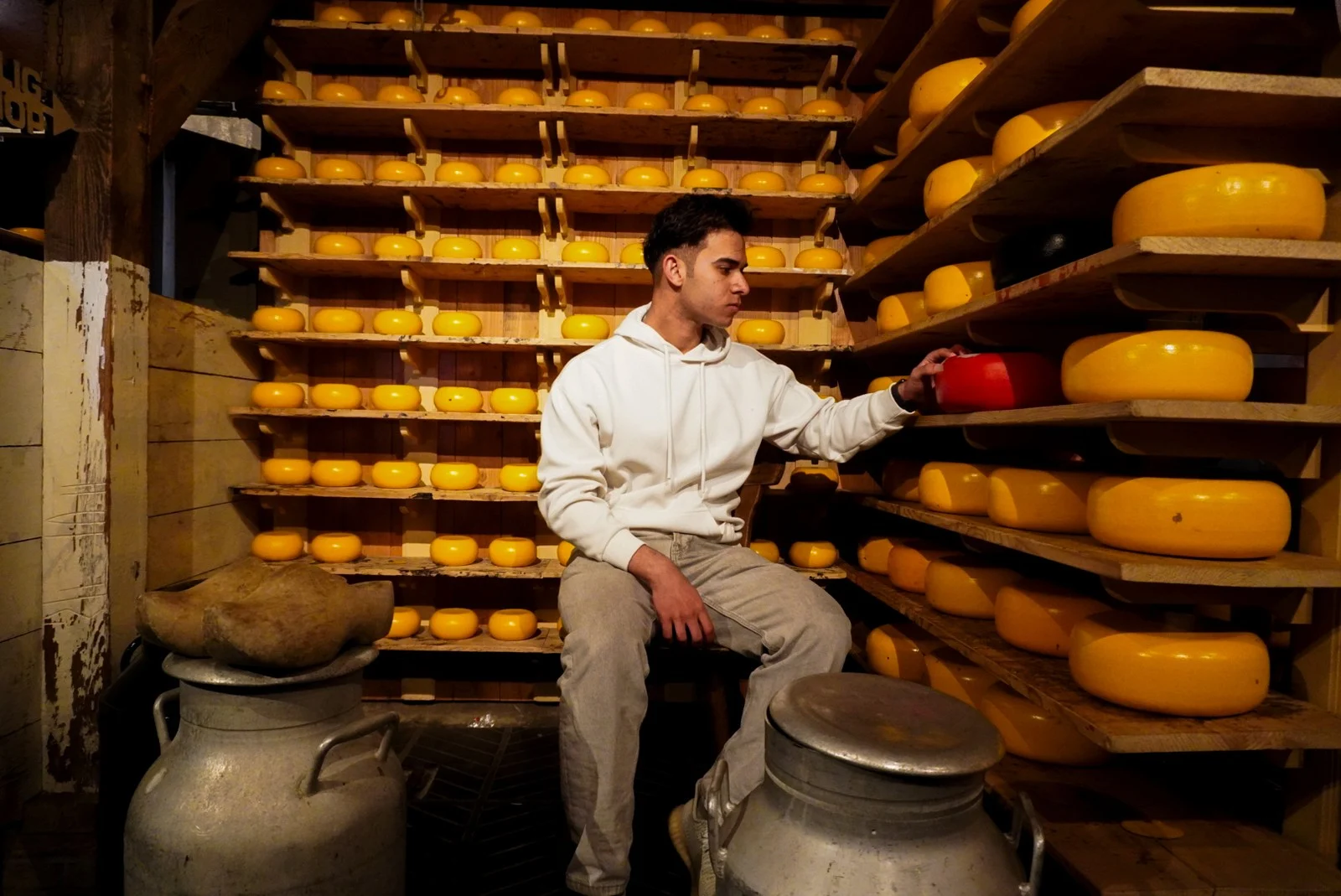 Hayder Aldaher seated among shelves of cheese wheels in Amsterdam